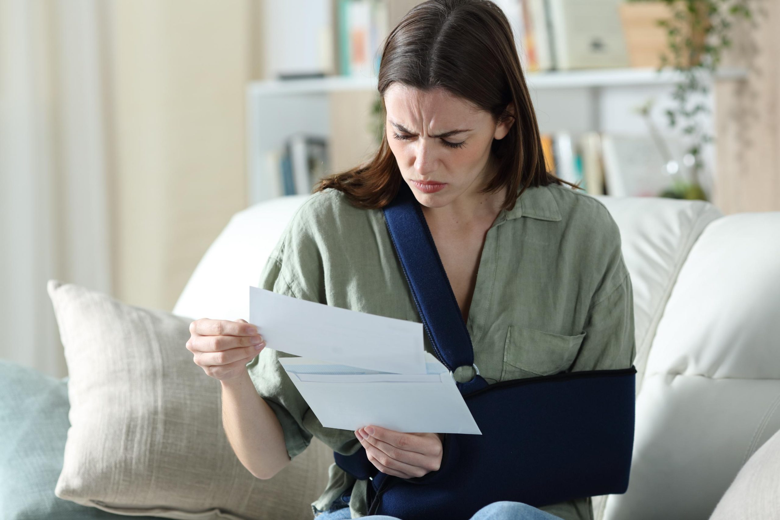 An adult woman reading insurance claim denial papers